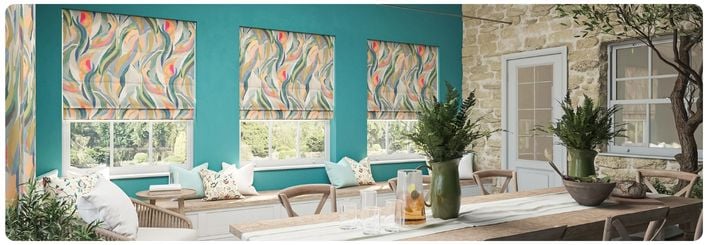 Green roller blinds with a floral pattern over large kitchen windows in a modern open plan kitchen