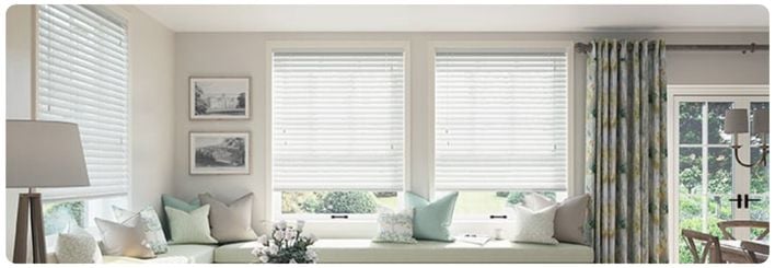 Green roller blinds with a floral pattern over large kitchen windows in a modern open plan kitchen