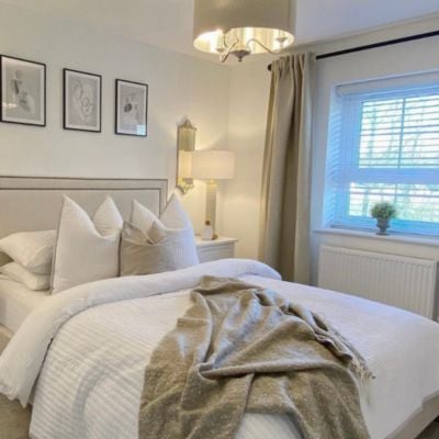 Beige curtains layered over white wooden Venetian blinds