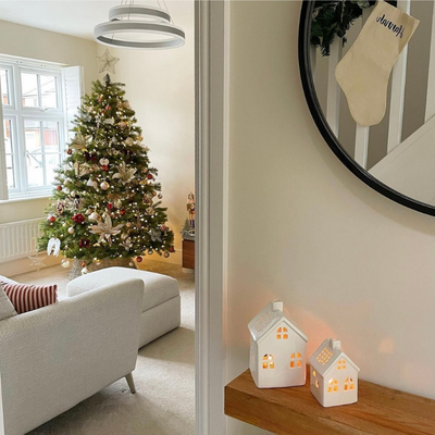 Red and gold Christmas tree in beige living room with white shutters.