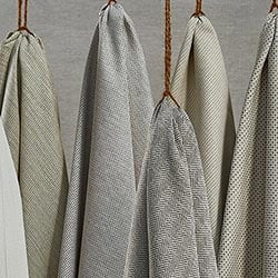 A collection of grey textured soft fabrics, hanging artfully on some twine.