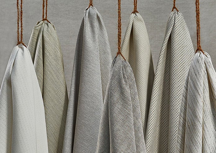 A collection of grey textured soft fabrics, hanging artfully on some twine.