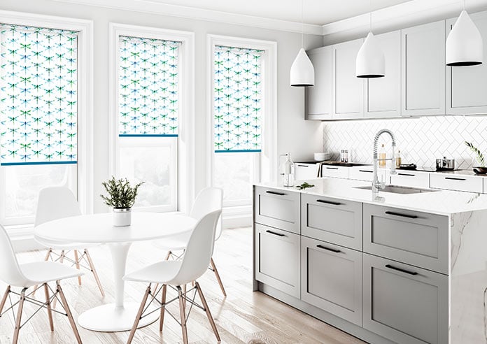 A green and blue dragonfly roller blind is shown in a clean, neutral kitchen/dining area.