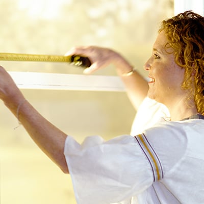 Woman measuring a window for blinds.