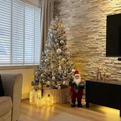 Snowy Christmas tree in grey living room with white wooden taped blinds.