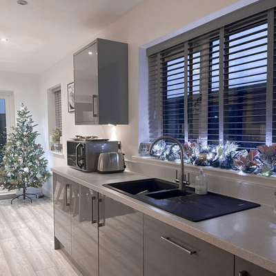 Christmas tree in glossy grey kitchen with grey wooden blinds.