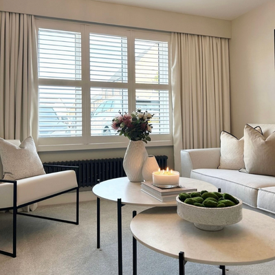 White wooden shutters paired with cream curtains in a neutral greige living room