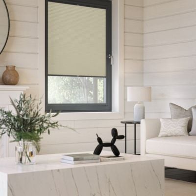 a warm, cream, Perfect Fit blind in a modern, white living room.