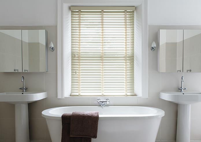 An image showing a cream taped wooden blind in a modern white bathroom