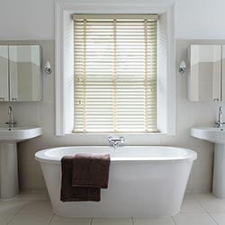 An image showing a cream taped wooden blind in a modern white bathroom
