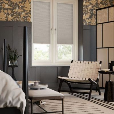 A brown, pleated stick-on blind on tilt and turn windows in a modern bedroom. 
