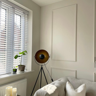 Neutral living room with wall panelling and white wooden Venetian blinds. 