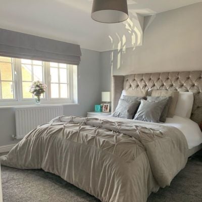 A grey and beige bedroom with a grey roman blind