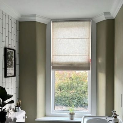 A green bathroom with a sheer, textured roman blind