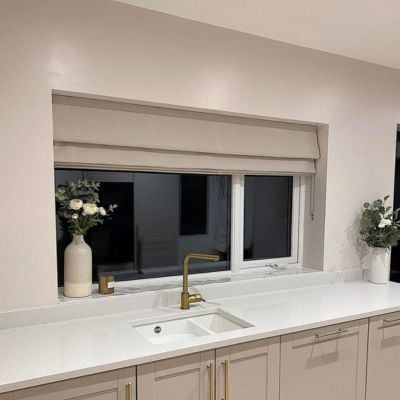 A beige kitchen with a beige roman blind in the window recess