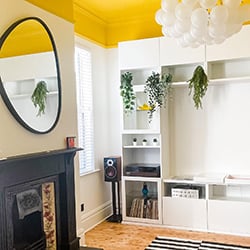 Modern living room with a yellow ceiling and white wooden blind in the window