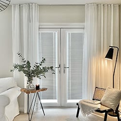 A very neutral themed living room with grey pleated blinds in the PVC doors and grey curtains
