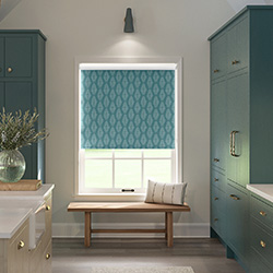 A teal blue roller blind is shown in a kitchen decorated with teal blue cabinets