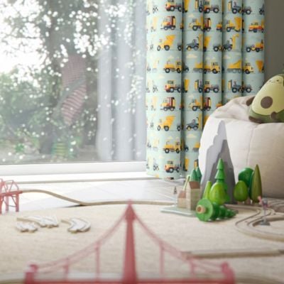 A blue curtains with yellow and grey tractors and trucks in a child's bedroom 