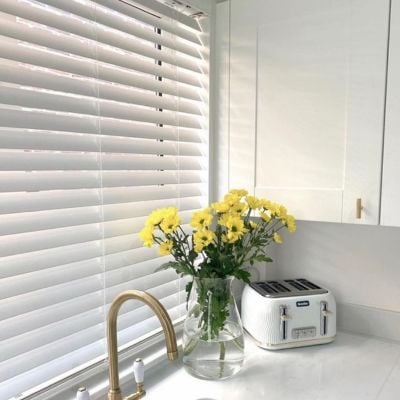 White, wooden blinds in a white kitchen.