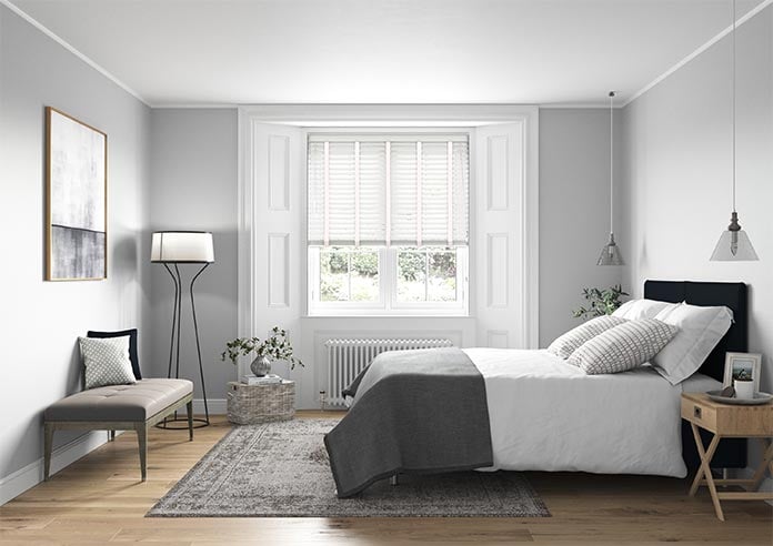 A bedroom image with a ecowood deluxe pure white wooden blind in the window