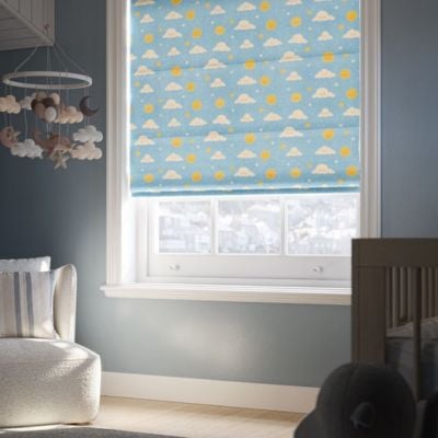 A blue roman blind with white cartoon clouds and yellow suns in a blue nursery 