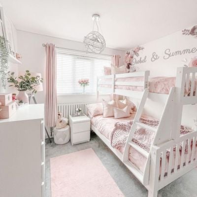 A pastel pink and white girls room with white wooden blinds and pale pink curtains
