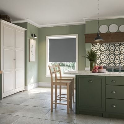 Dark grey, blackout roller blind in a green kitchen. 