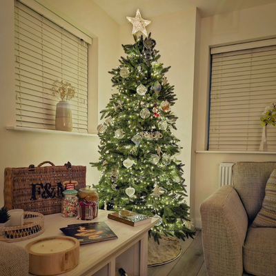 Red and green traditional Christmas living room with red stockings and garland on the fireplace and white wooden Venetian blinds in the window.
