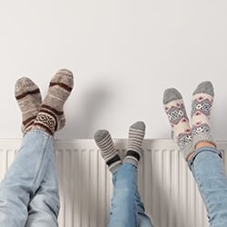 An image showing a family warming their feet on a radiator